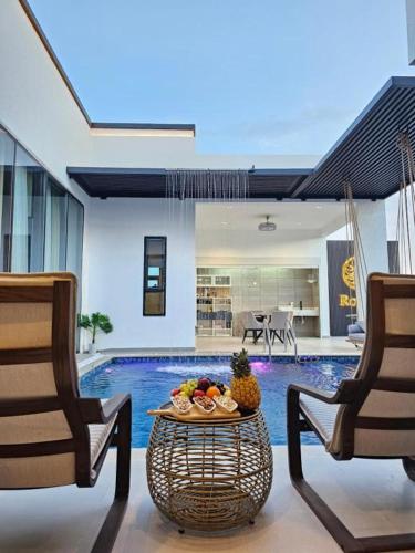a living room with a table and two chairs and a pool at Rosella Chalet 2 in Jabal Al Akhdar