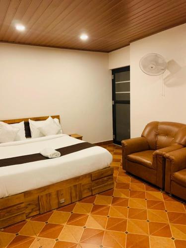 a bedroom with a bed and a leather couch at Vythiri Misty Wind Holiday Homes in Vythiri