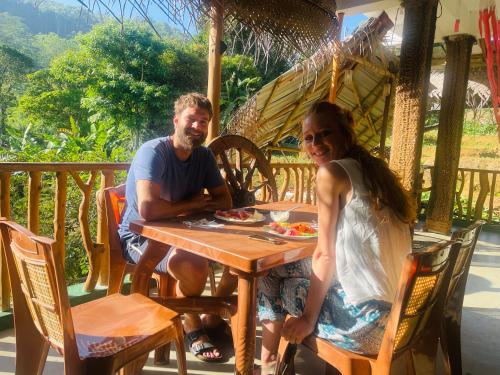 a man and a woman sitting at a table at Ella Rock Grun Cottage in Ella