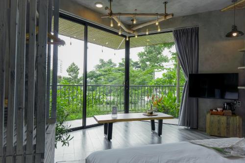 a bedroom with a bed and a table and a balcony at Babylon Mini Resort in Vung Tau