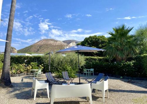 a table and chairs with an umbrella and mountains at Dolcevita Villa in Vulcano in Vulcano
