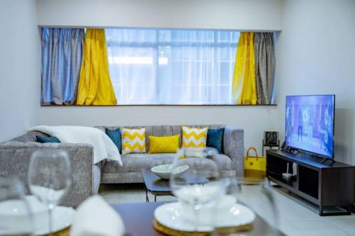 a living room with a couch and a tv at Skynest Residences Entire Furnished Apartment, Westlands in Nairobi