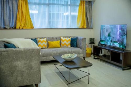 a living room with a couch and a flat screen tv at Skynest Residences Entire Furnished Apartment, Westlands in Nairobi