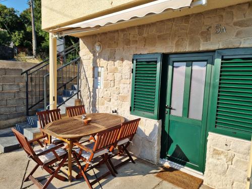 a wooden table and chairs outside a building with a green door at Holiday home Barci in Crikvenica