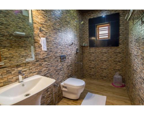 a bathroom with a white toilet and a sink at Wayanad Fort Resort, Noolpuzha, Kerala in Muthanga
