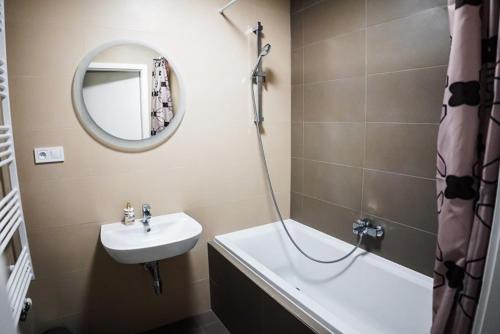 a bathroom with a sink and a mirror and a tub at AH Designe in Košice