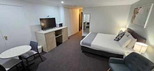 a hotel room with a bed and a table and chairs at Tea Gardens Motel in Tea Gardens
