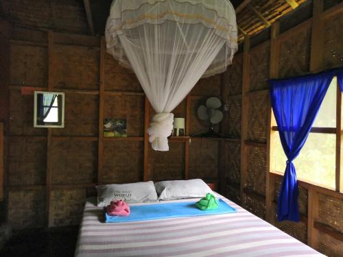 a bedroom with a bed in a room with a curtain at Nuts Huts in Loboc