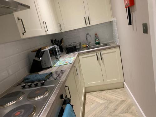 a small kitchen with white cabinets and a stove at Cambridge Suites in Harmondsworth