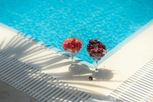 two glasses filled with cherries sitting next to a swimming pool at WEST HOUSE EXCLUSIVE HOTEL in Göcek
