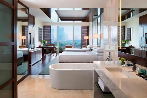 a bathroom with a bath tub and a bedroom at JW Marriott Hotel Hanoi in Hanoi
