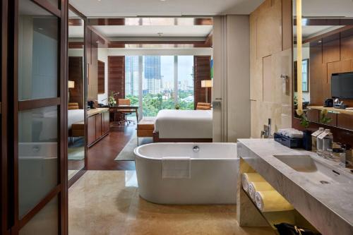 a bathroom with a bath tub and a bedroom at JW Marriott Hotel Hanoi in Hanoi