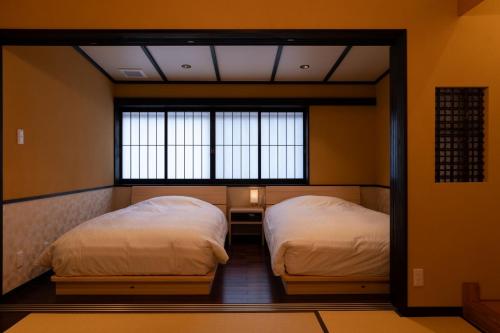 duas camas num quarto com duas janelas em 一日一組の隠れ宿　てらかわ em Kinosaki