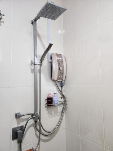 a shower in a white tiled bathroom at Wakaf Bharu Garden Stay Semi-D By UJ in Kota Bharu
