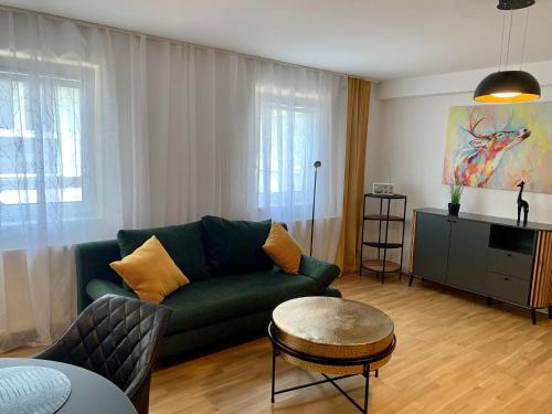 a living room with a green couch and a table at Ruhiges Apartment mit Terrasse im Zentrum St. Pölten in Sankt Pölten