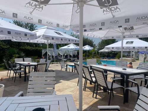 a group of tables and chairs with white umbrellas at ElGringo Clisura Dunarii in Moldova Nouă