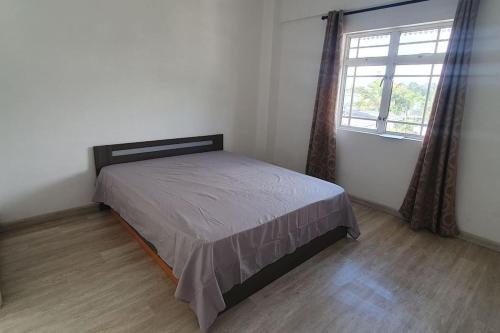 a bedroom with a bed in a room with a window at Appartment in town in Curepipe