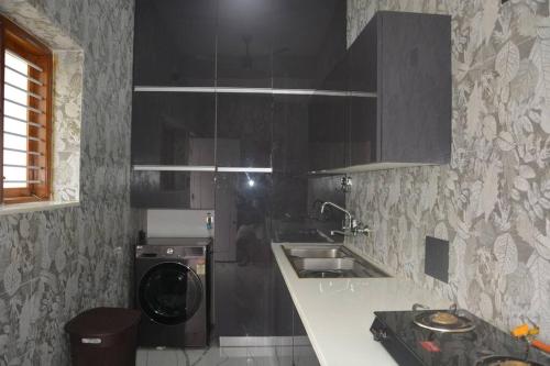 a kitchen with a sink and a washing machine at Earth - Luxurious 5 BHK AC Villa at Mysore in Mysore