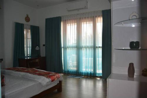 a bedroom with a bed and a large window with green curtains at Earth - Luxurious 5 BHK AC Villa at Mysore in Mysore