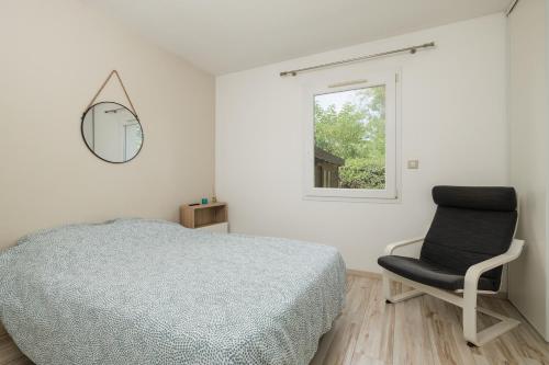 ein Schlafzimmer mit einem Bett, einem Stuhl und einem Fenster in der Unterkunft L Entre2mers in Sadirac