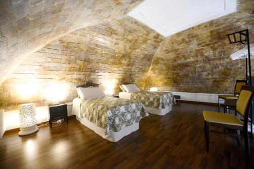 Un dormitorio con dos camas y una pared de ladrillo. en AL DUOMO, Dimora Storica, en Matera
