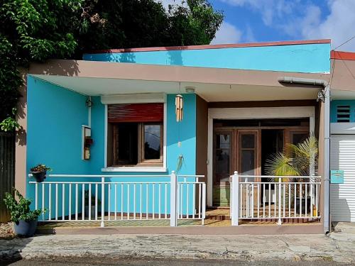 ein blaues Haus mit einem weißen Zaun davor in der Unterkunft Kaz'Azula in Saint-François