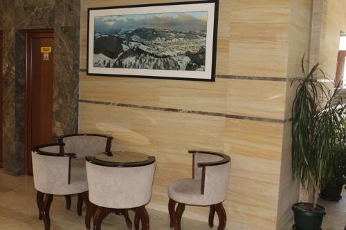 three chairs and a table in a room with a wall at IN Hotel Zlatar ex Zlatarski Biseri in Nova Varoš