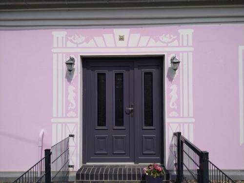 een roze en wit huis met een zwarte deur bij Wohnung Nr 4 in Bargischow