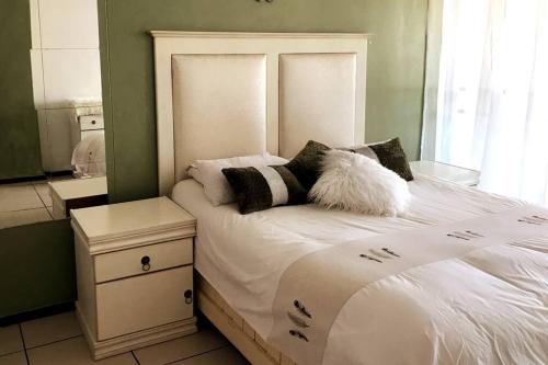 Modern style Apartment in Pretoria-Central في بريتوريا: غرفة نوم بسرير ذو شراشف ووسائد بيضاء