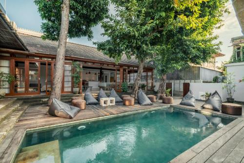 Una piscina con almohadas y árboles frente a una casa. en Batu Belig Living Apartment Seminyak, en Seminyak