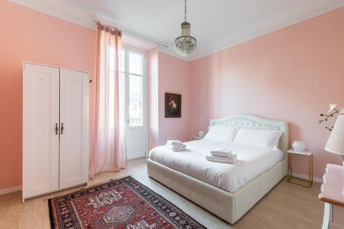 a bedroom with a white bed and a pink wall at West Park Suite With Parking by Holiday Solutions in Como