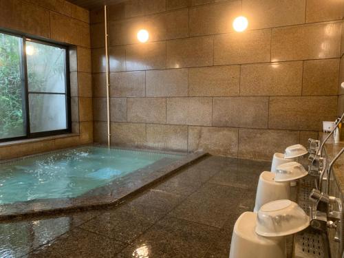 a bathroom with a jacuzzi tub with a window at APA Hotel Kofu Minami in Kofu