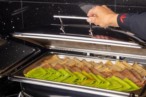 a person is putting a tray of food in an oven at Hotel Meta Resort & Vine SPA in Szczyrk