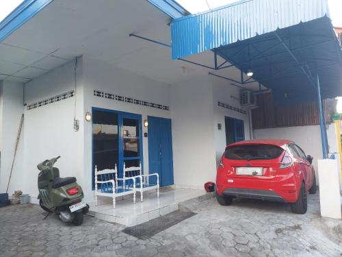 une voiture rouge garée devant un immeuble avec scooter dans l'établissement FHStay Malioboro, à Timuran