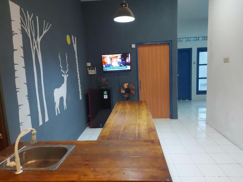 Il comprend une cuisine avec un évier et une télévision murale. dans l'établissement FHStay Malioboro, à Timuran