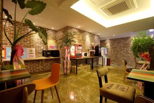 um quarto com cadeiras e mesas e uma parede de tijolos em Hotel H2 em Ulsan