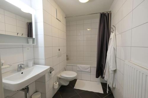 a white bathroom with a sink and a toilet at Wonderful holiday home on the shore of Walensee in Quarten