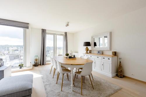 a white kitchen with a wooden table and chairs at B&B Le Murmure de l'eau - Chambre d'hôte Urbaine - Namur in Namur