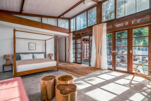 1 dormitorio con 1 cama y ventanas grandes en Batu Belig Living Managed by CPM Bali, en Seminyak