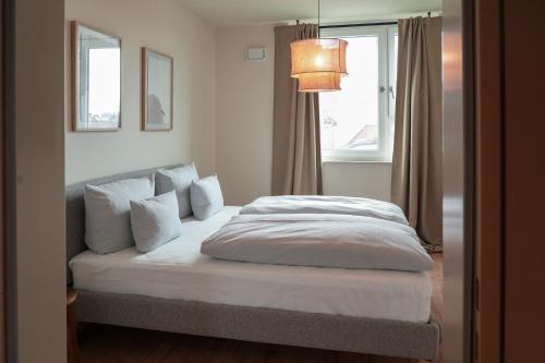 a bedroom with a bed with white sheets and a window at Cocoon Sendlinger Tor in Munich