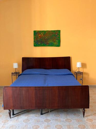 sypialnia z drewnianym łóżkiem i obrazem na ścianie w obiekcie Residenza Arrivabene Sicily w mieście Valdina