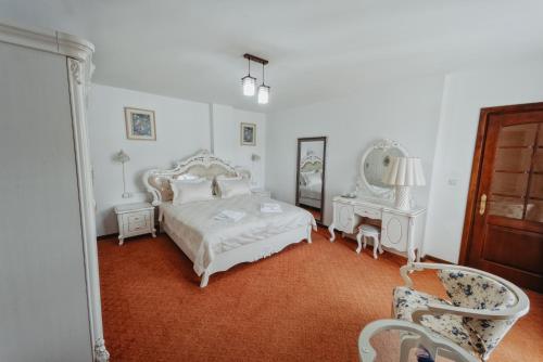 a white bedroom with a bed and a mirror at Complex Turistic Constantin Bucovina in Câmpulung Moldovenesc