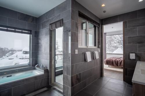 ein Bad mit einer Badewanne und einem Fenster in der Unterkunft Song Saa Chalet in Niseko