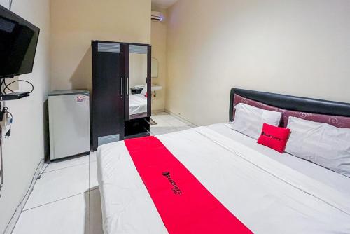 um quarto com uma cama grande e um cobertor vermelho em RedDoorz At Graha 99 Simomulyo em Surabaya