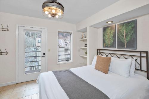 a bedroom with a white bed and two windows at River Location 2 blocks to lift 7 &to the Gondola in Telluride