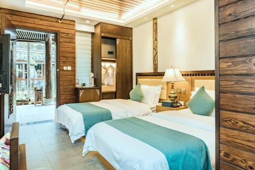 麗江市にある丽江束河元年别院 Yuannian Lijiangのベッド2台と窓が備わるホテルルームです。