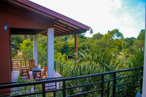 a house with a balcony with chairs and trees at Darshani Lodge in Sigiriya