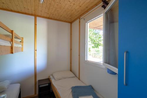 um pequeno quarto com uma cama e uma janela em Village Vacances Passion La Bayette em Le Pradet