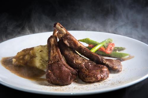 a plate of food with meat and vegetables on a table at Mii Hotel Srinakarin in Bangna