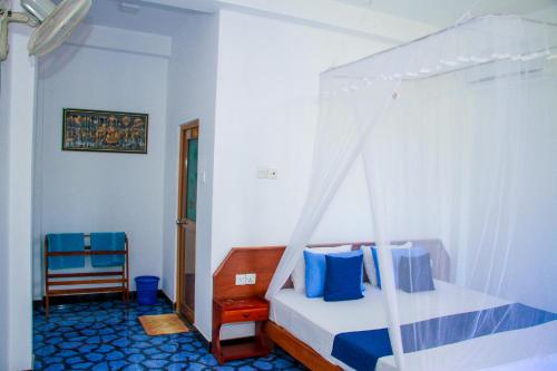 1 dormitorio con cama con dosel y silla en Darshani Lodge, en Sigiriya